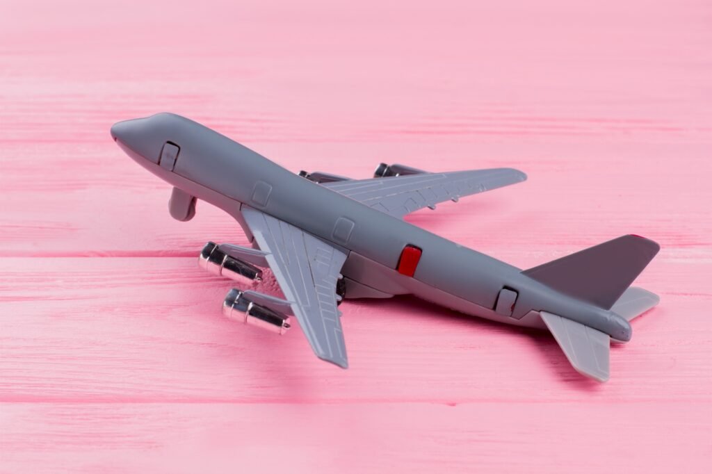 Flat lay toy airplane on pink wooden background.
