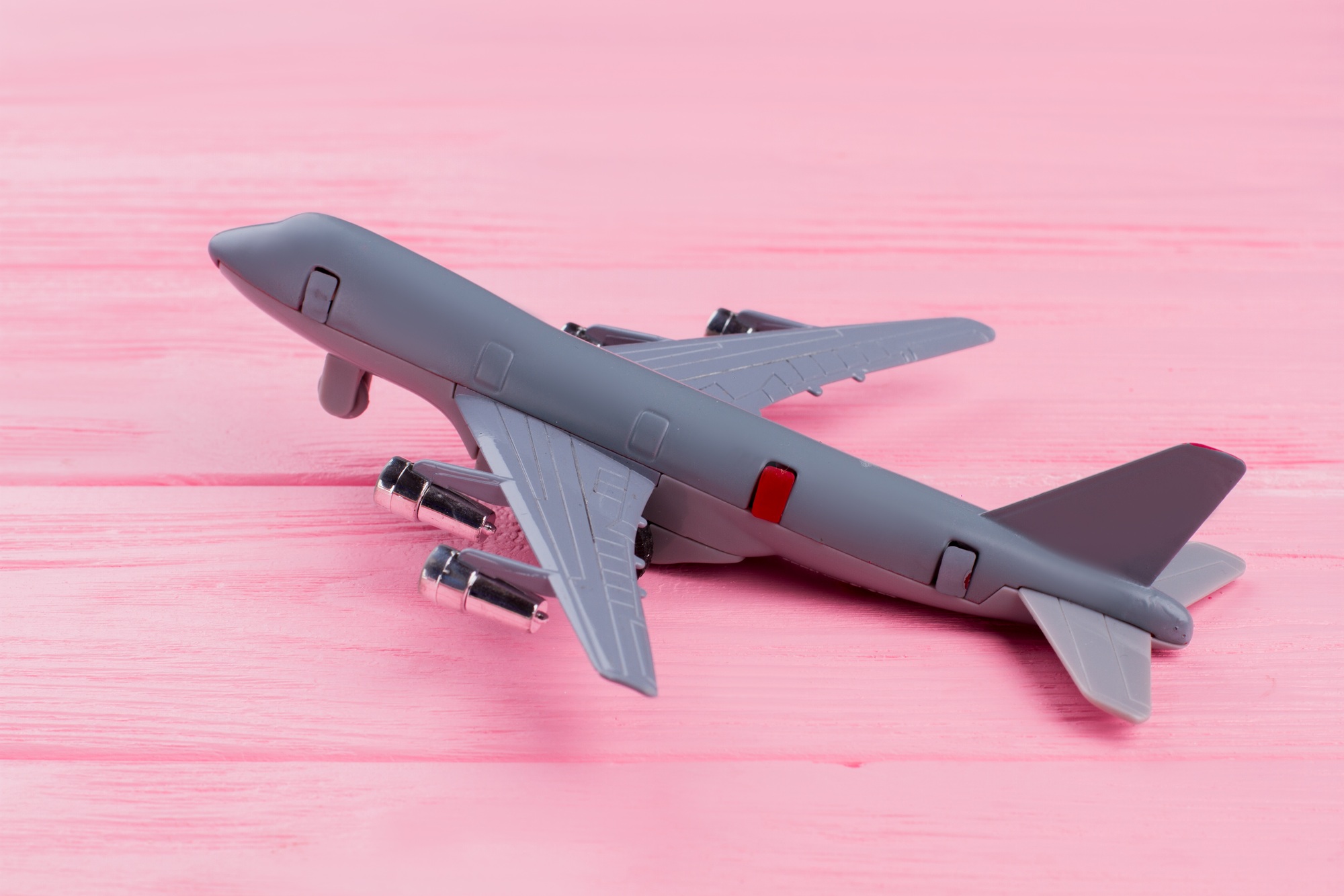 Flat lay toy airplane on pink wooden background.